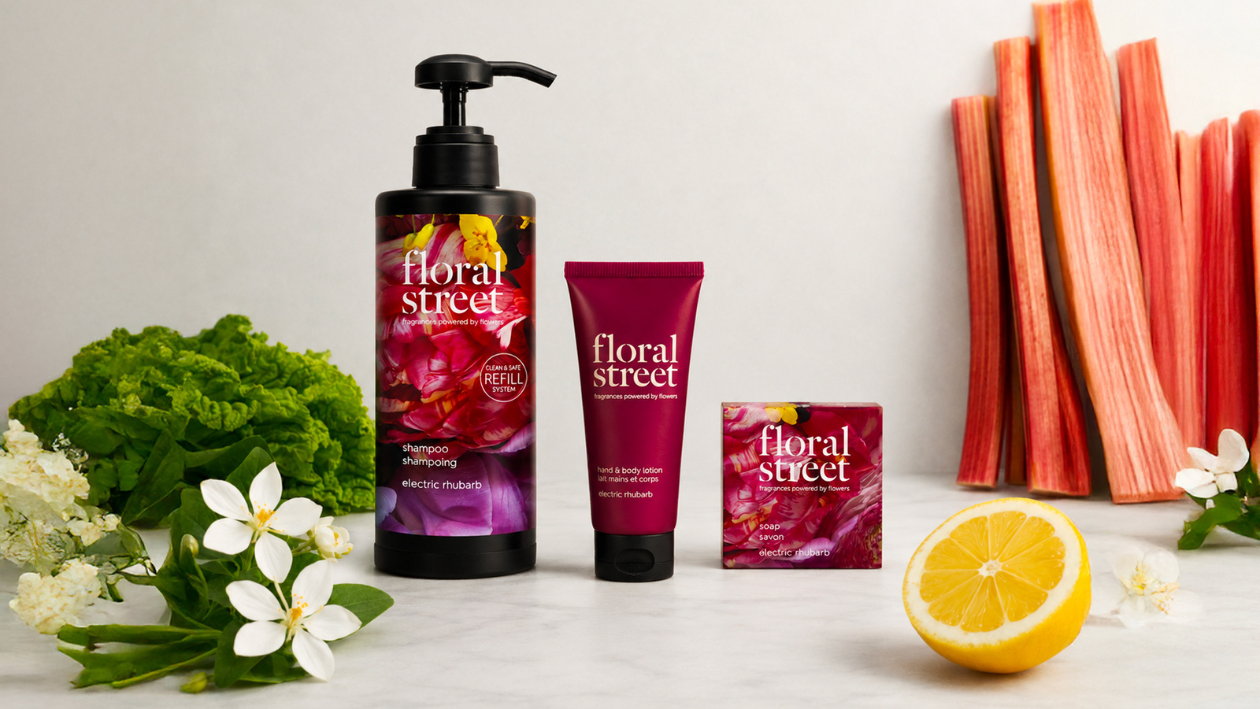 Floral Street Produtos de banho e cuidados corporais da Electric Rhubarb, incluindo champô recarregável, loção para as mãos e para o corpo e sabonete, apresentados com talos de ruibarbo frescos, flores brancas, folhas verdes e limão num fundo simples.