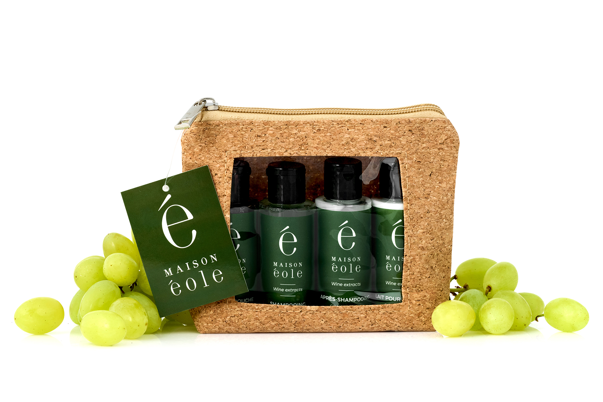 Maison Éole travel amenities kit in a cork pouch, displayed with fresh green grapes.