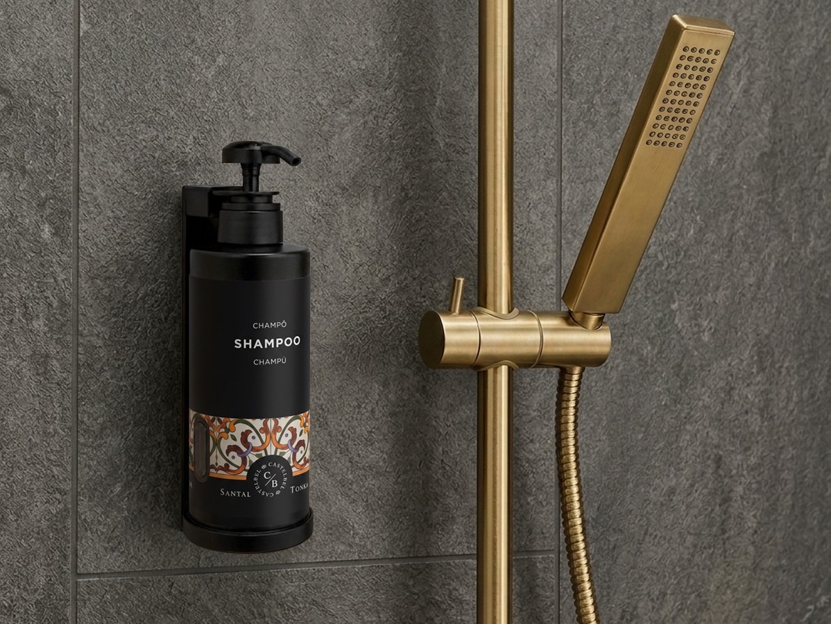 Luxury shampoo dispenser mounted in a modern shower with brushed gold fixtures.