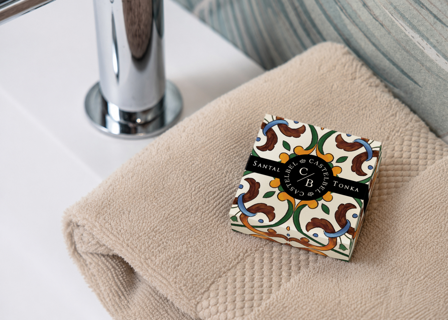 Castelbel Santal Tonka soap box displayed on a folded towel beside a bathroom sink.