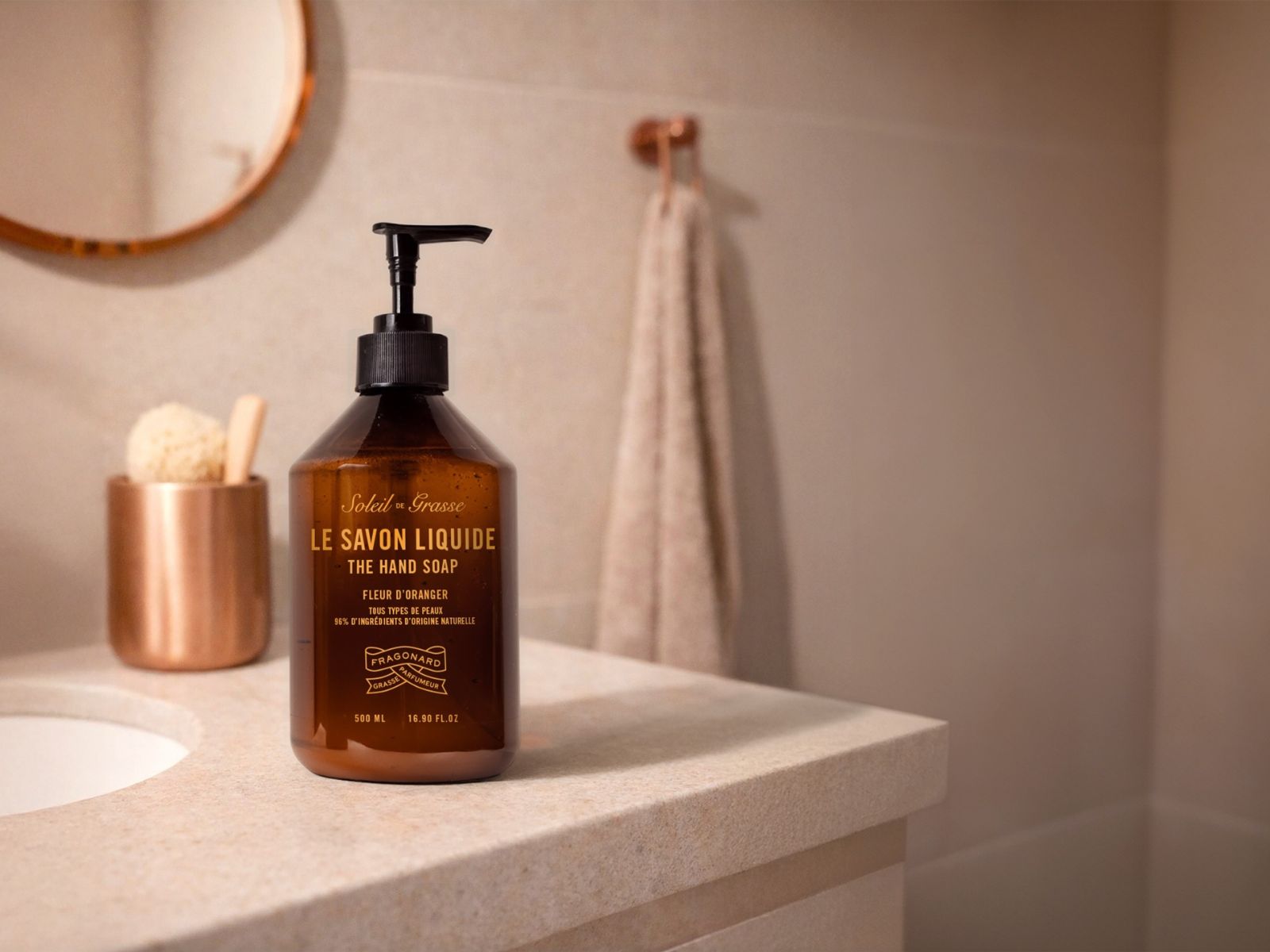 Fragonard Soleil de Grasse orange blossom liquid hand soap in a luxury bathroom setting with warm natural light.