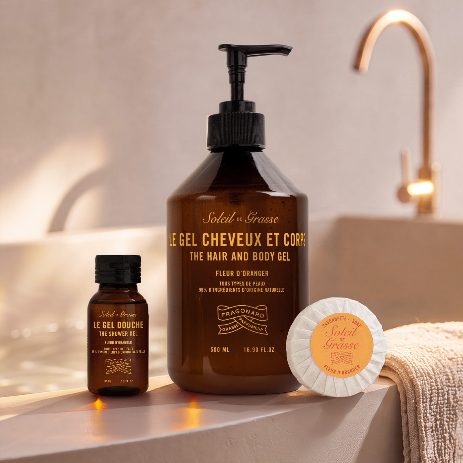 Fragonard Soleil de Grasse orange blossom hair and body gel, shower gel and soap displayed on a luxury bathroom countertop with warm natural light.